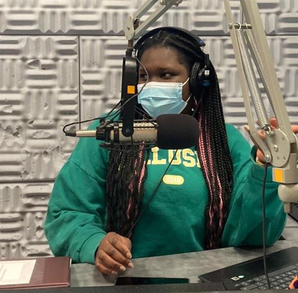A student sits behind a microphone and in front of a wall covered with soundproofing material. They are deep in conversation while recording a fascinating radio show for KECG.